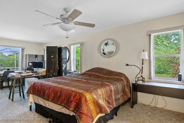 bedroom with multiple windows, ceiling fan, and light colored carpet