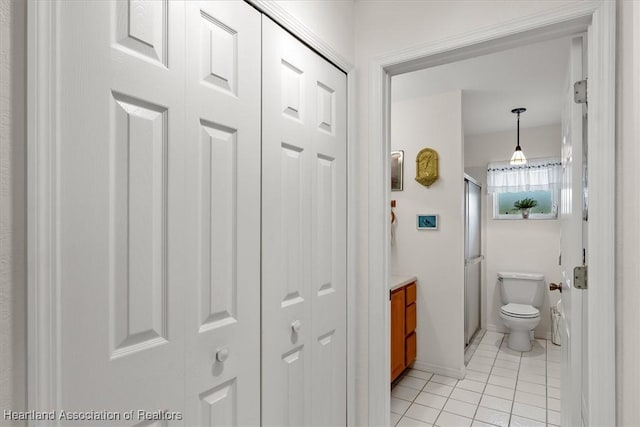 bathroom with tile patterned flooring, vanity, toilet, and a shower with shower door