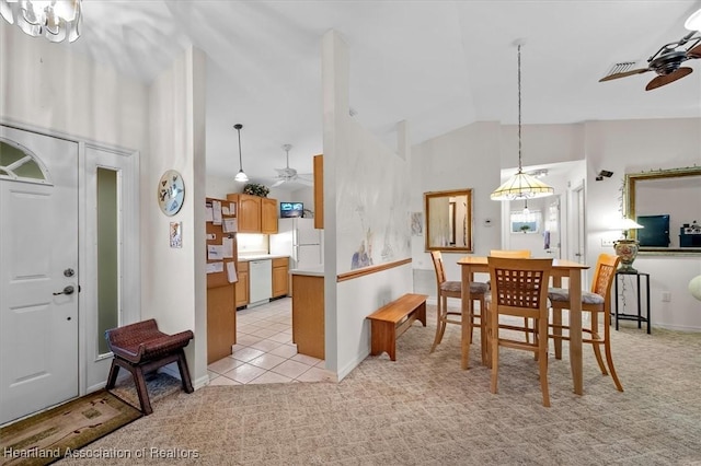 dining area featuring ceiling fan with notable chandelier, light colored carpet, and high vaulted ceiling