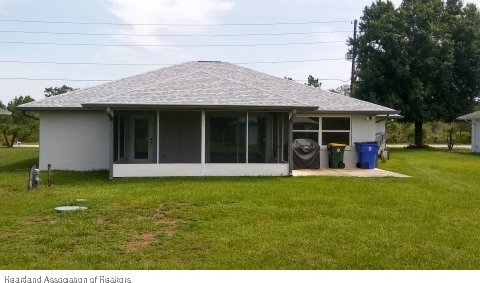 rear view of property featuring a sunroom and a lawn