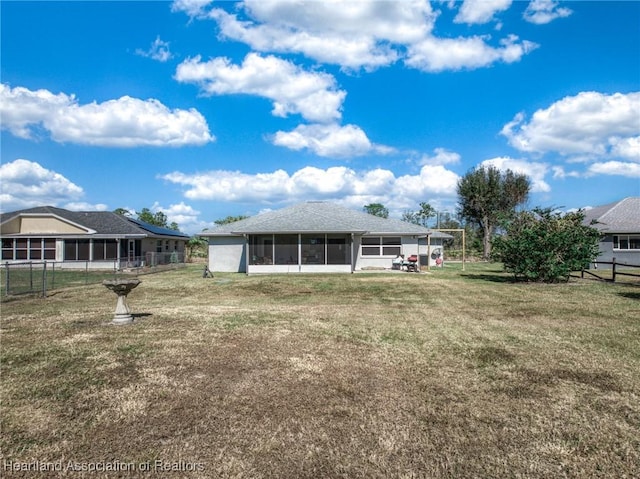 back of property with a sunroom and a lawn