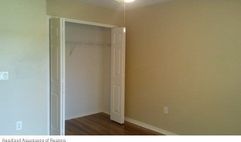 unfurnished bedroom featuring dark hardwood / wood-style flooring and a closet