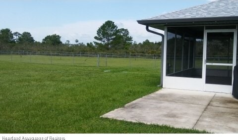 view of yard with a patio area, a sunroom, and a rural view