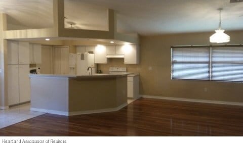 kitchen with pendant lighting, white cabinetry, white refrigerator with ice dispenser, and dark wood-type flooring