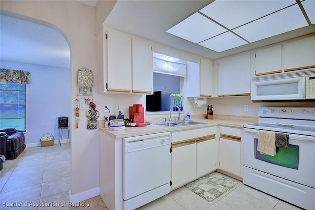 kitchen with white appliances, light countertops, a sink, and white cabinets