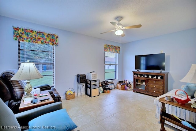 living area with light tile patterned floors, baseboards, and a ceiling fan