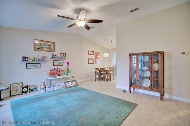 recreation room featuring lofted ceiling, ceiling fan, light tile patterned floors, visible vents, and baseboards