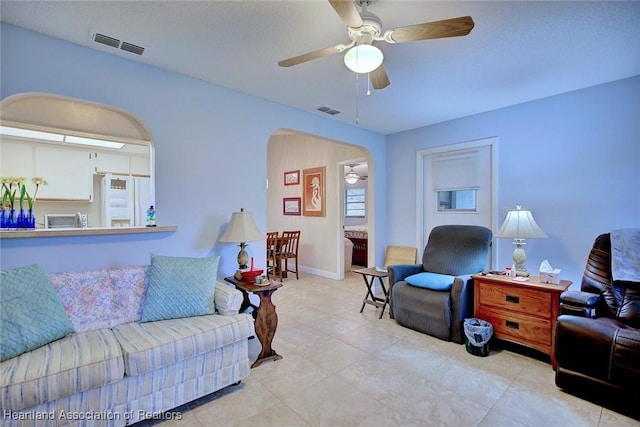 living room featuring arched walkways, visible vents, and ceiling fan