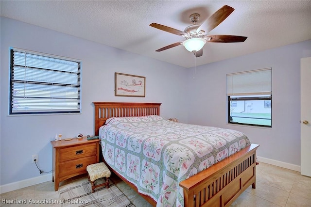 bedroom with a textured ceiling, ceiling fan, light tile patterned flooring, and baseboards