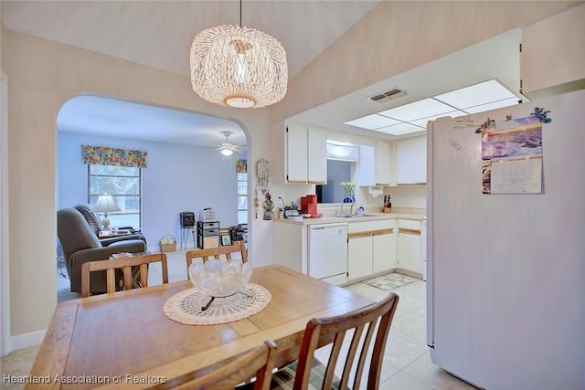 dining area with arched walkways, light tile patterned floors, ceiling fan with notable chandelier, and visible vents