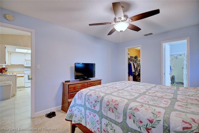 bedroom with light tile patterned floors, baseboards, visible vents, a walk in closet, and a textured ceiling