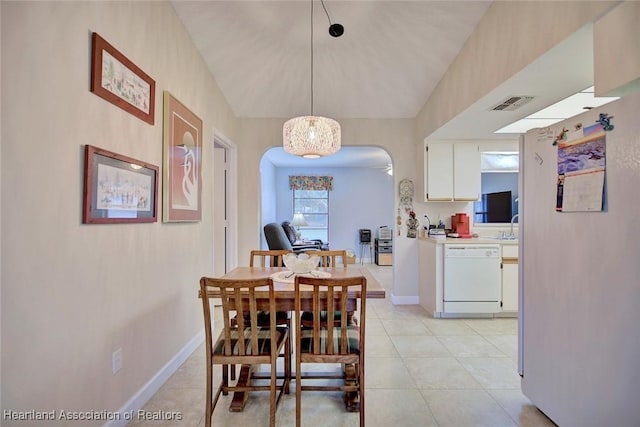 dining room featuring arched walkways, light tile patterned floors, lofted ceiling, visible vents, and baseboards