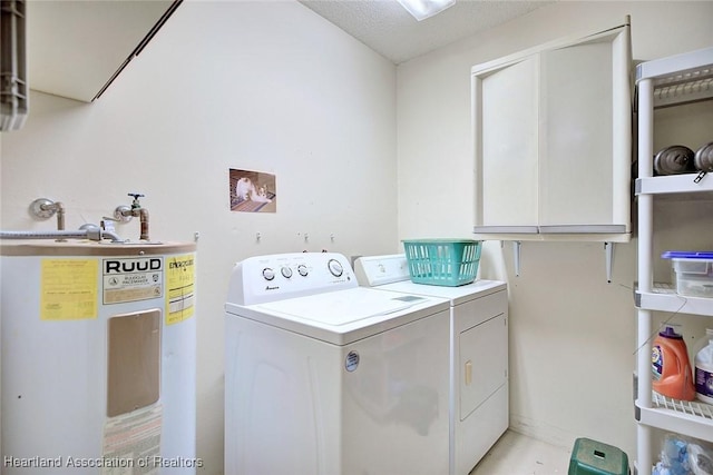 laundry area with washing machine and dryer, water heater, cabinet space, and a textured ceiling