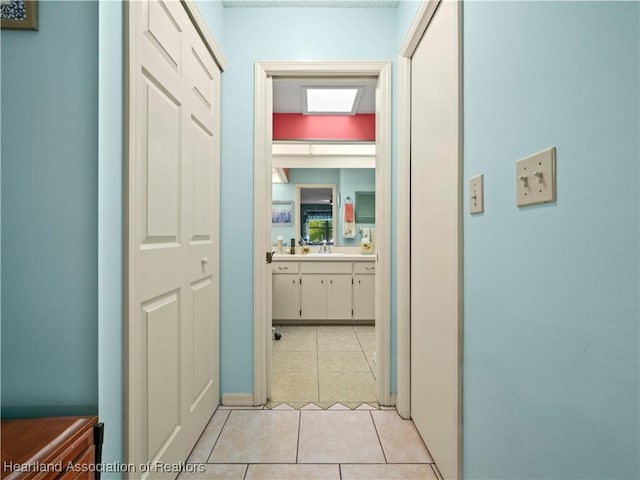 corridor featuring light tile patterned floors and sink