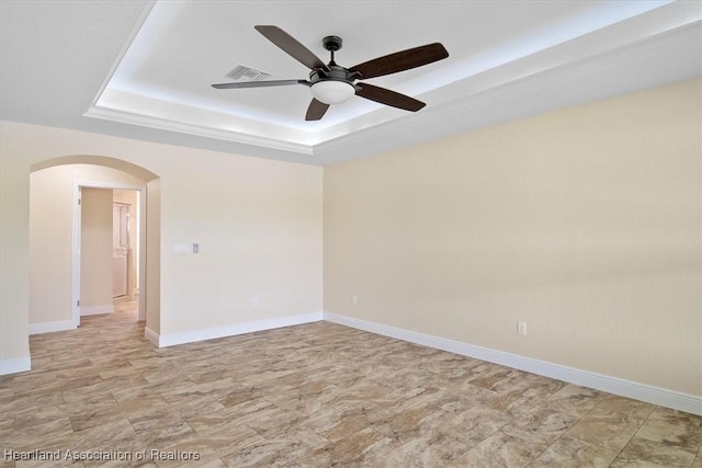 unfurnished room with a raised ceiling and ceiling fan