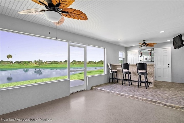 sunroom with ceiling fan, a healthy amount of sunlight, and a water view