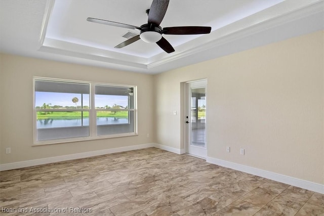 unfurnished room featuring ceiling fan, a water view, and a tray ceiling