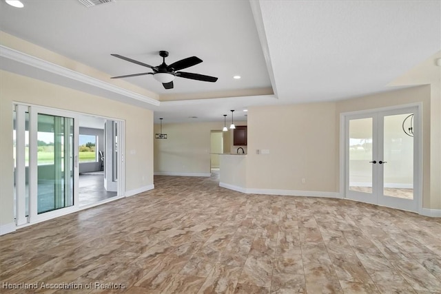 unfurnished living room with a tray ceiling, ceiling fan, and french doors