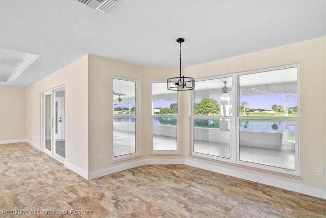 unfurnished dining area with a healthy amount of sunlight, a water view, a tray ceiling, and a chandelier