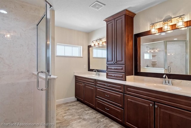 bathroom featuring vanity, a shower with shower door, and a textured ceiling