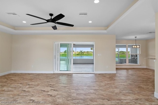 spare room with a raised ceiling, a healthy amount of sunlight, and ceiling fan with notable chandelier