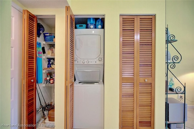 laundry area featuring light tile patterned floors and stacked washer and clothes dryer