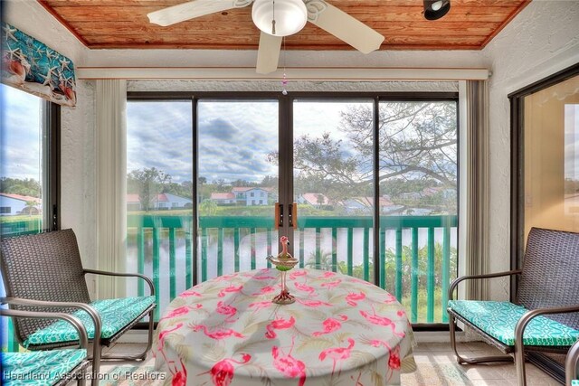 sunroom featuring a water view, wood ceiling, and a wealth of natural light