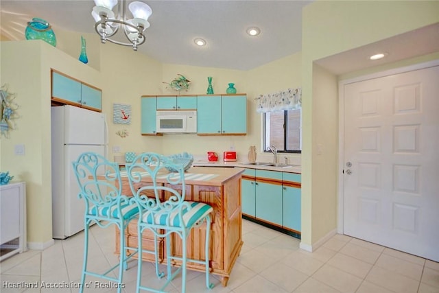 kitchen featuring white appliances, sink, a chandelier, a kitchen island, and light tile patterned flooring