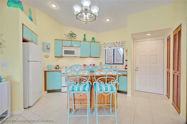 kitchen with blue cabinetry, a kitchen island, a chandelier, white appliances, and light tile patterned floors