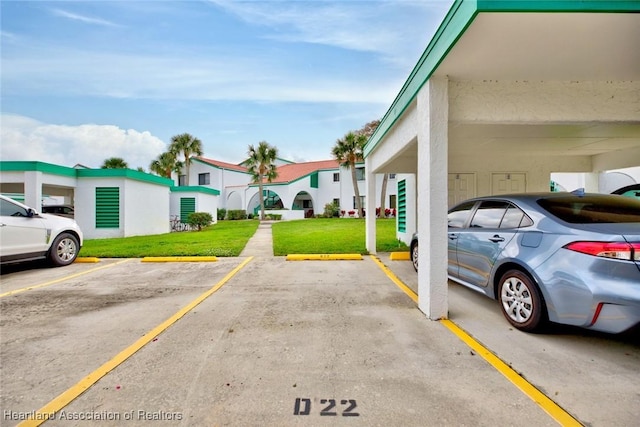 view of parking featuring a yard and a carport