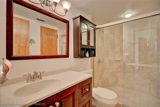 bathroom featuring vanity, an inviting chandelier, toilet, and walk in shower