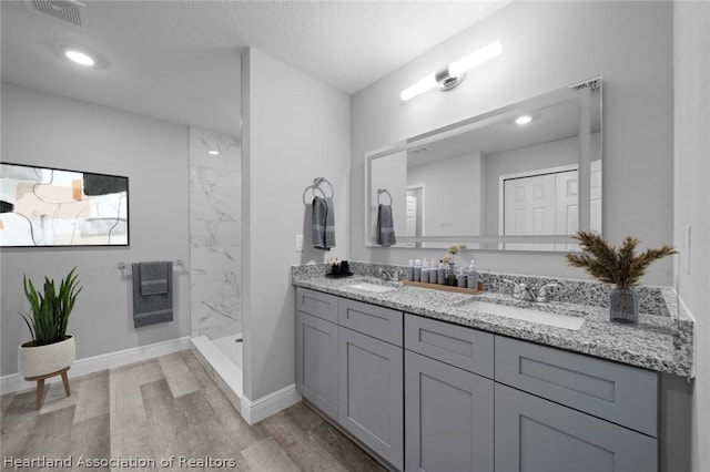 bathroom featuring a tile shower, hardwood / wood-style floors, vanity, and a textured ceiling