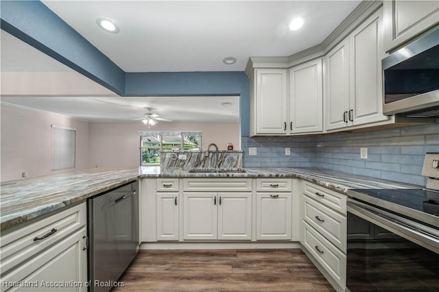 kitchen with stainless steel appliances, a sink, backsplash, and light stone countertops