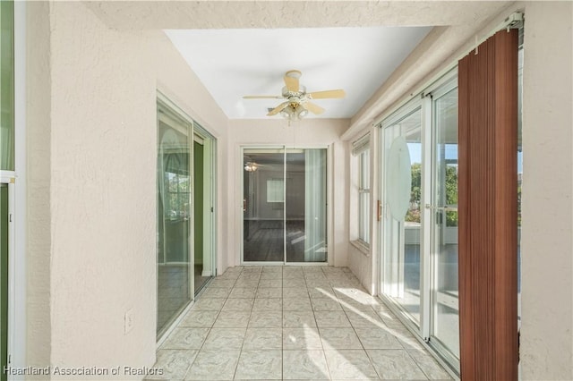 unfurnished sunroom featuring ceiling fan