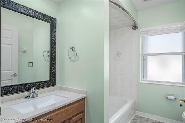 bathroom with toilet, vanity, baseboards, and shower / bathtub combination