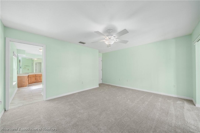 spare room featuring light carpet, a ceiling fan, visible vents, and baseboards