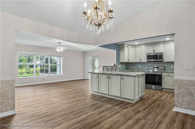 kitchen with tasteful backsplash, appliances with stainless steel finishes, open floor plan, wood finished floors, and ceiling fan with notable chandelier