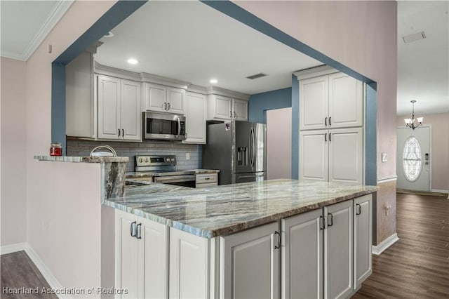 kitchen with visible vents, appliances with stainless steel finishes, dark wood-style flooring, light stone countertops, and backsplash