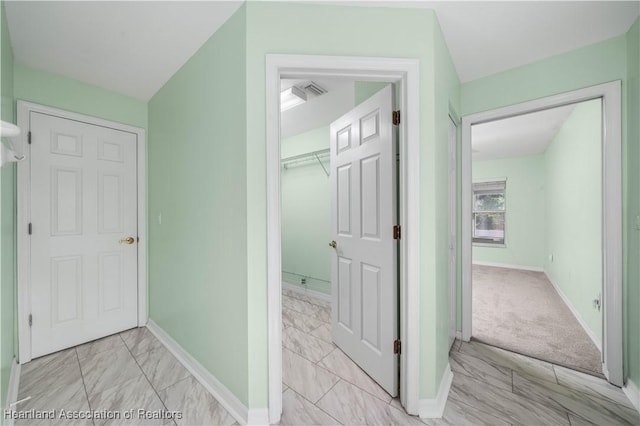 hall with marble finish floor, visible vents, and baseboards