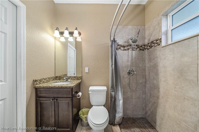 bathroom with a tile shower, vanity, and toilet