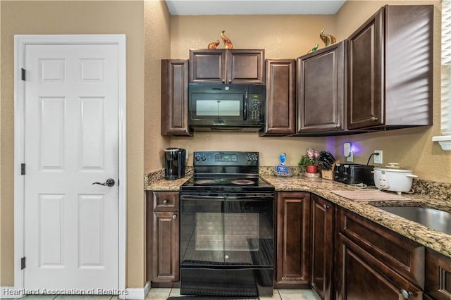 kitchen with black appliances, light stone counters, and dark brown cabinetry