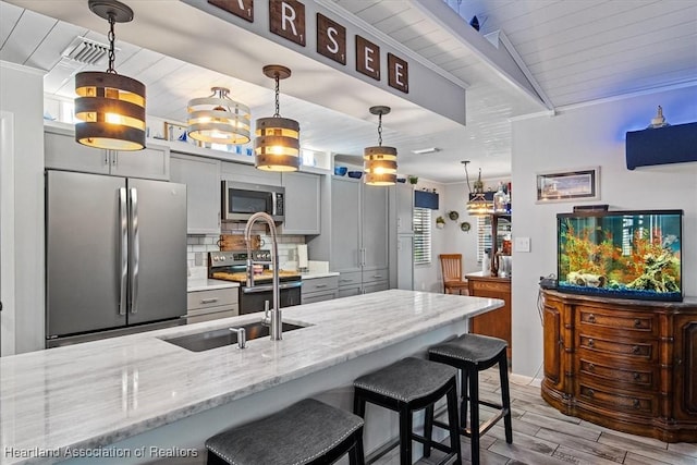 kitchen featuring light stone counters, appliances with stainless steel finishes, gray cabinets, backsplash, and wood tiled floor