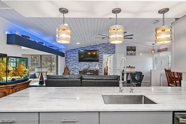 kitchen featuring lofted ceiling, a sink, visible vents, open floor plan, and decorative light fixtures