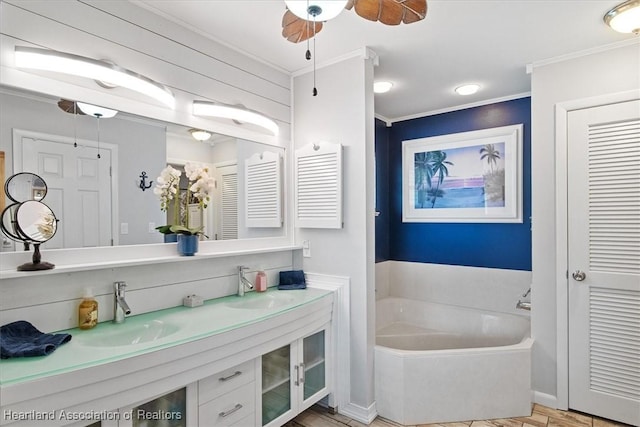 bathroom with a closet, a sink, a bath, and crown molding