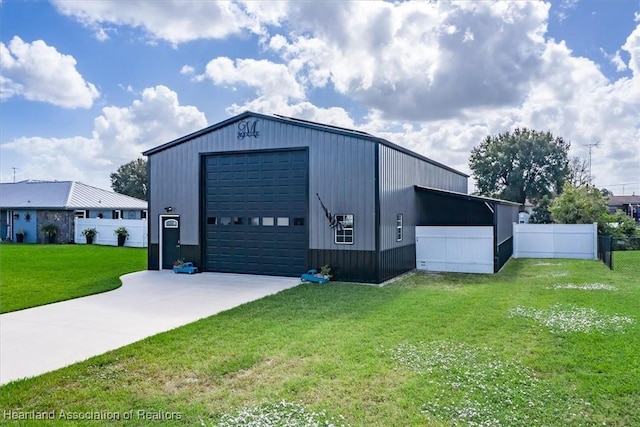 view of outdoor structure featuring an outbuilding, concrete driveway, and fence