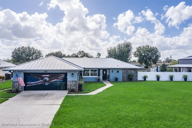 ranch-style home featuring concrete driveway, metal roof, an attached garage, fence, and a front lawn