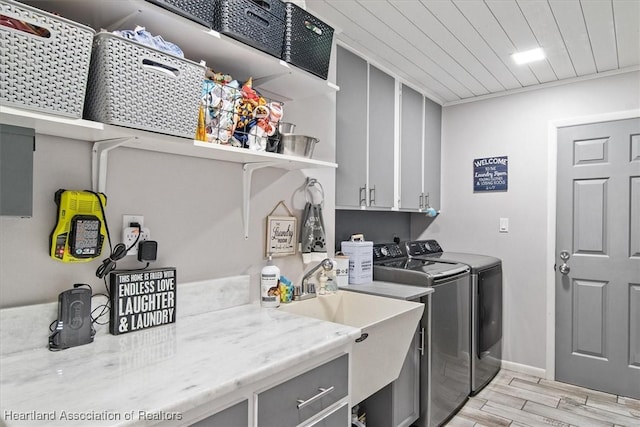 clothes washing area featuring cabinet space, wooden ceiling, independent washer and dryer, wood tiled floor, and a sink