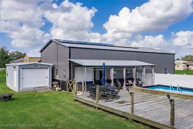 back of property with a fenced in pool, a lawn, an outbuilding, fence, and a deck