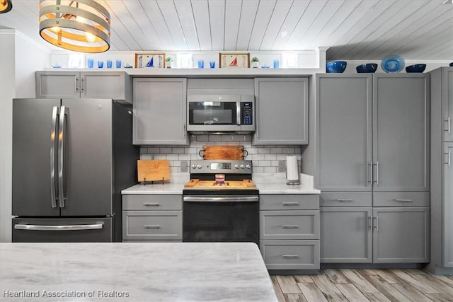 kitchen featuring appliances with stainless steel finishes, light countertops, backsplash, and gray cabinetry