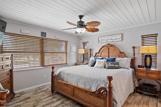 bedroom featuring baseboards, wood finished floors, a ceiling fan, and crown molding